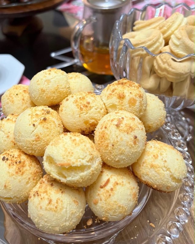 Pães de queijo três queijos gratinados por cima, numa travessa de cristal